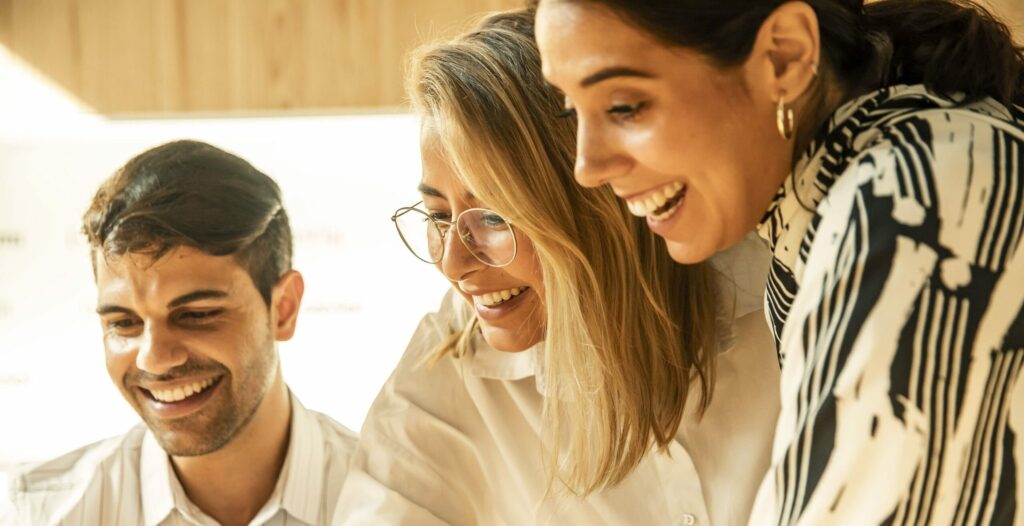 Equipa diversa de líderes empresariais em reunião colaborativa - homem e duas mulheres profissionais a sorrir