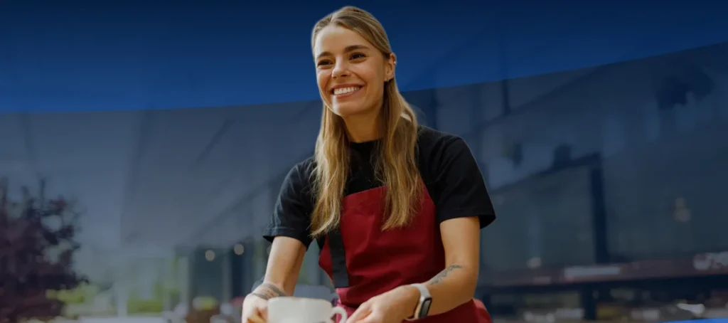 Profissional de hotelaria com avental vermelho a servir cliente em esplanada - recrutamento e formação setor hoteleiro Portugal