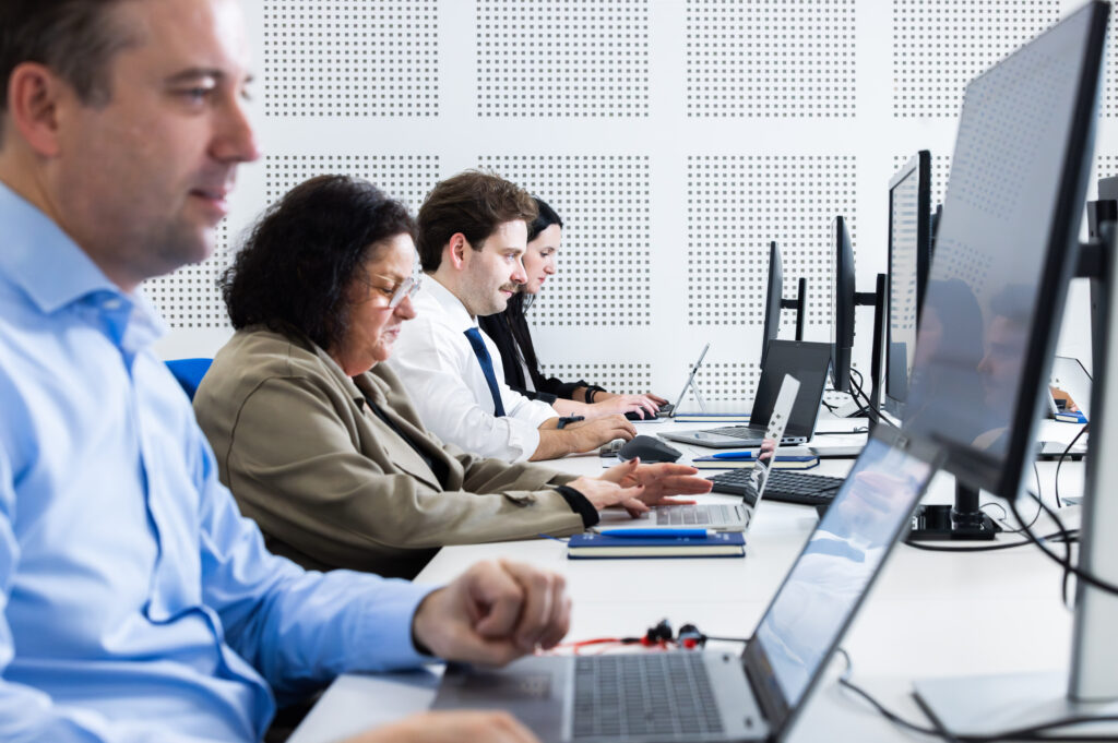 Profissionais em ambiente de escritório a trabalhar em computadores durante o período de contratações na Páscoa 2025.