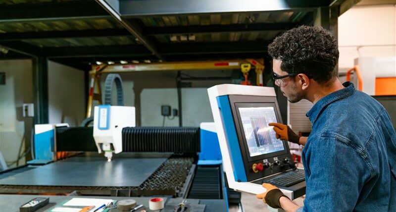 Profissional a operar máquina industrial automatizada com tecnologia digital numa fábrica